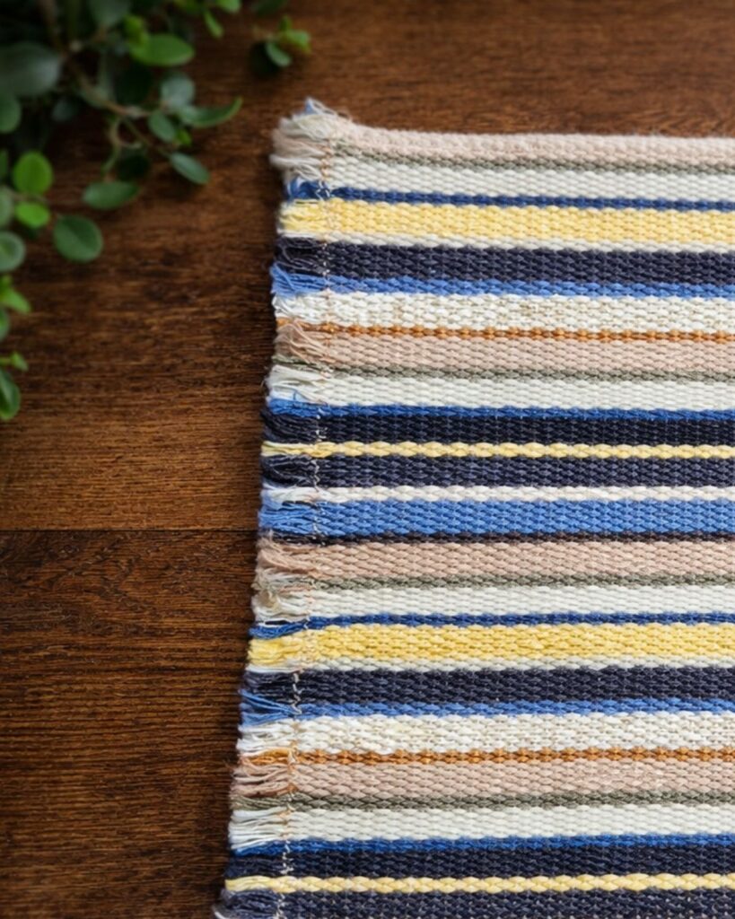 Detailaufnahme der Streifenstruktur eines handgewebten Untersetzers von Wiedengold.