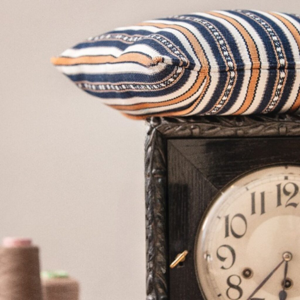 Handgewebtes Kissen von Wiedengold in dunkelblauen und ockerfarbenen Streifen, inszeniert als ruhiger Akzent kultivierter Wohnkultur.