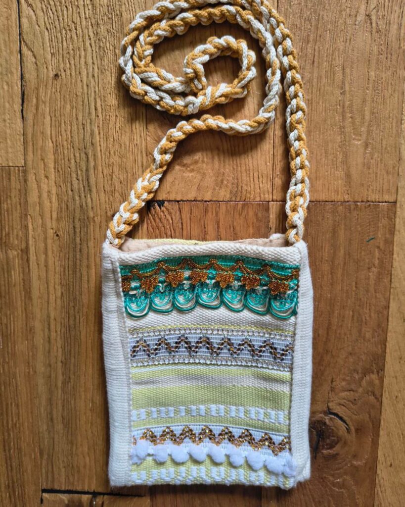 Handgewebte Handtasche aus Naturmaterialien in Türkis, Gelb und Weiß mit Streifenstruktur und feinen Borten.