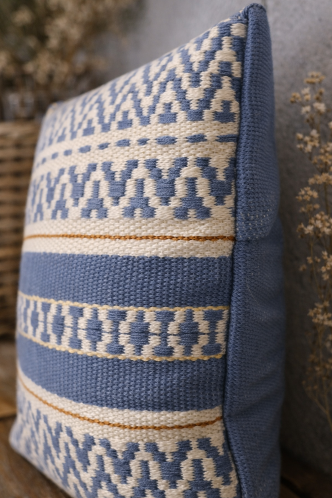 Detailaufnahme eines handgewebten Kissens mit Streifen in Blau, Weiß und Ocker.