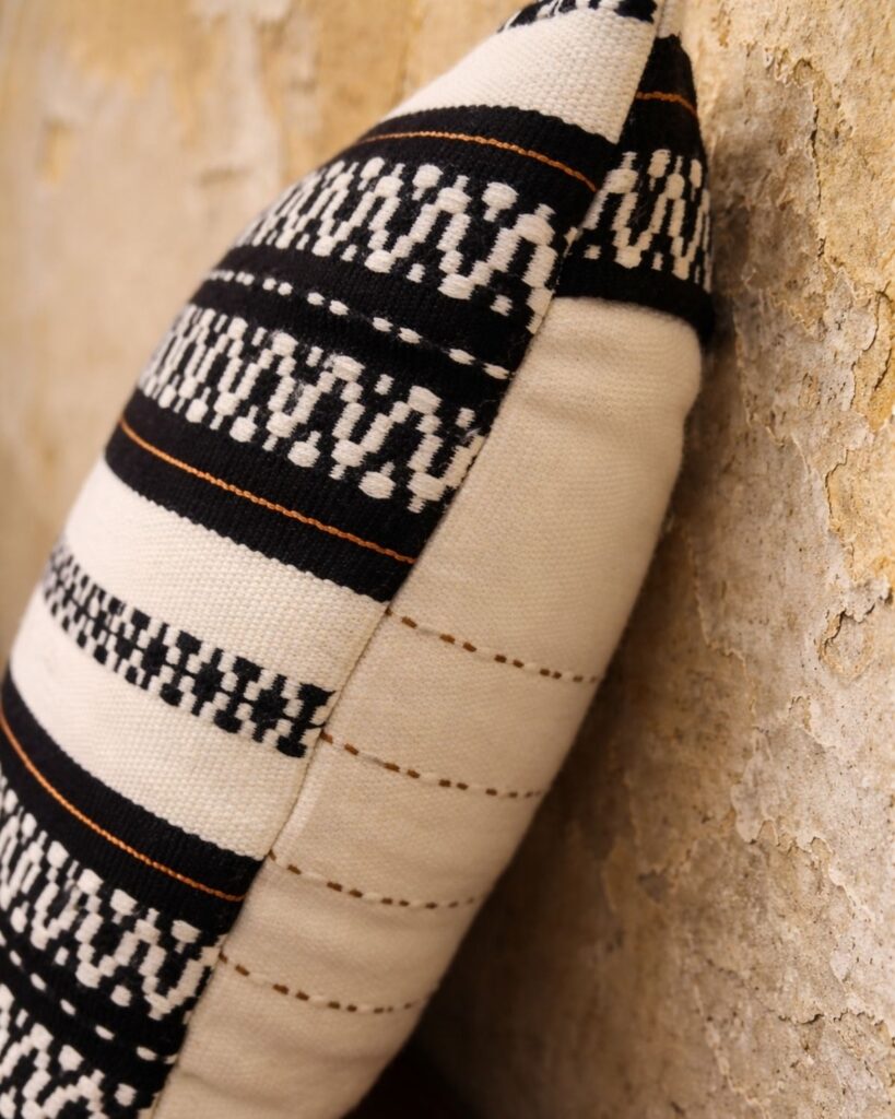 Detailaufnahme eines handgewebten Kissens mit grafischer Streifenstruktur in Schwarz und Weiß.