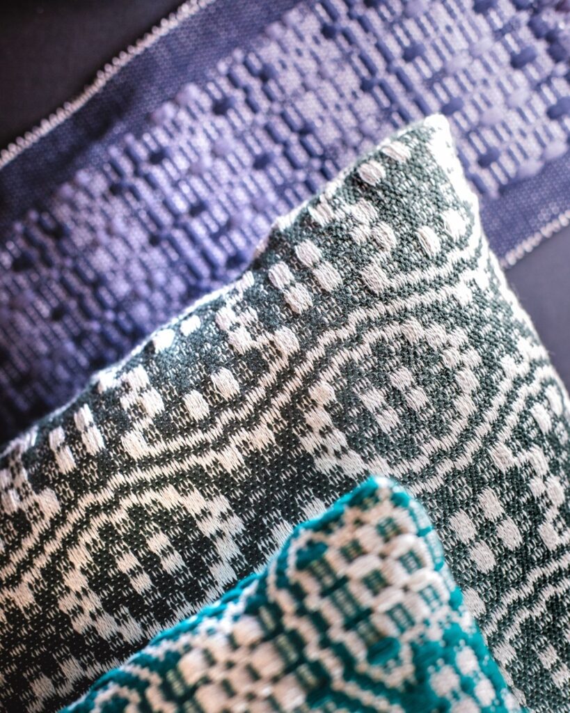 Handgewebte Kissen von Wiedengold in grün-blau-türkisen Mustervariationen.