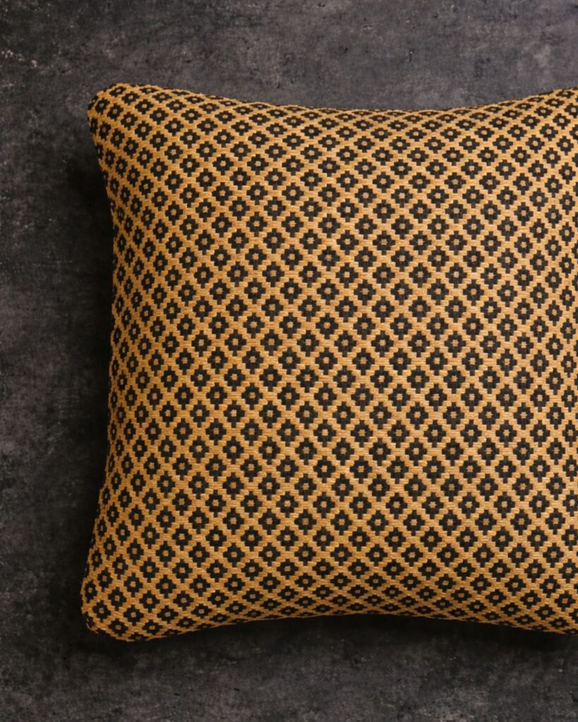 Handgewebtes Kissen von Wiedengold mit feiner Ornamentstruktur in Gelb und Schwarz.