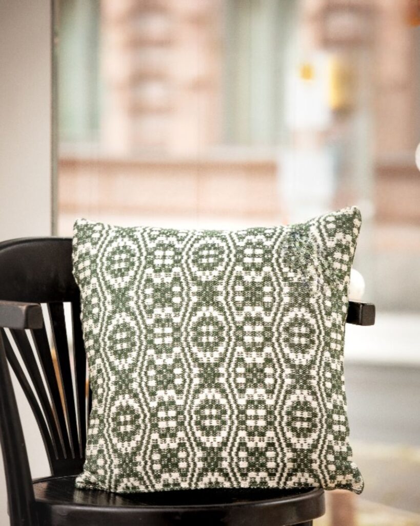 Handgewebtes Kissen von Wiedengold mit ornamentaler Struktur in Grün und Weiß aus Baumwolle und Viskose.