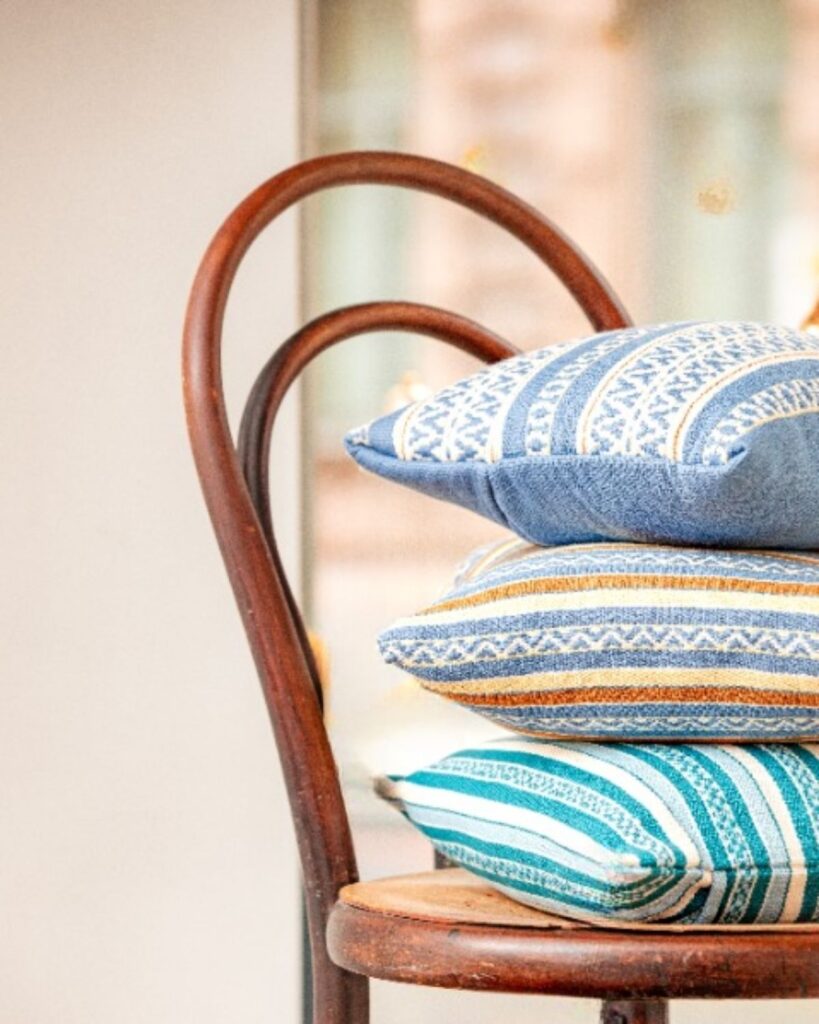 Drei handgewebte Kissen von Wiedengold in feinen Streifenvariationen – ruhiger Akzent kultivierter Wohnkultur.