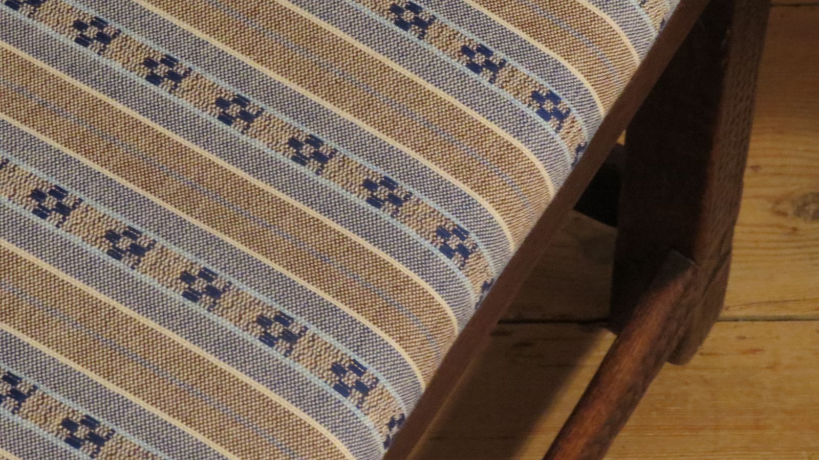 Detailaufnahme der Webstruktur eines handgewebten Möbelbezugstoffes von Wiedengold mit ruhiger Streifenornamentik.