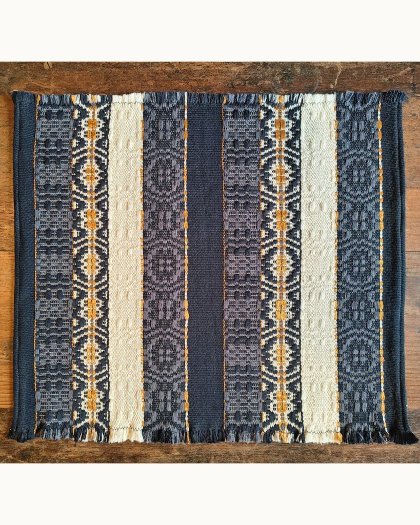 Handgewebter Tischläufer aus Wolle und Viskose von Wiedengold in Dunkelblau, Weiß und Gold mit ornamentalen Streifen.