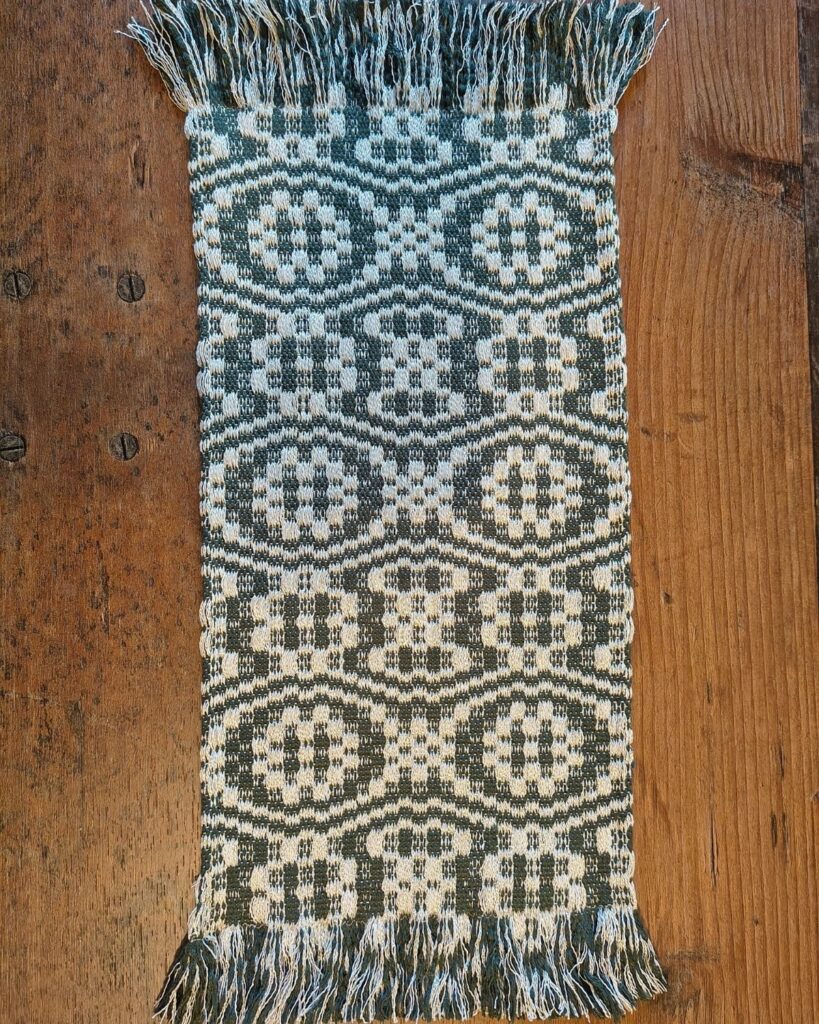 Handgewebter Tischläufer aus Baunwolle und Viskose in Grün und Weiß mit ornamentaler Struktur und Fransen.