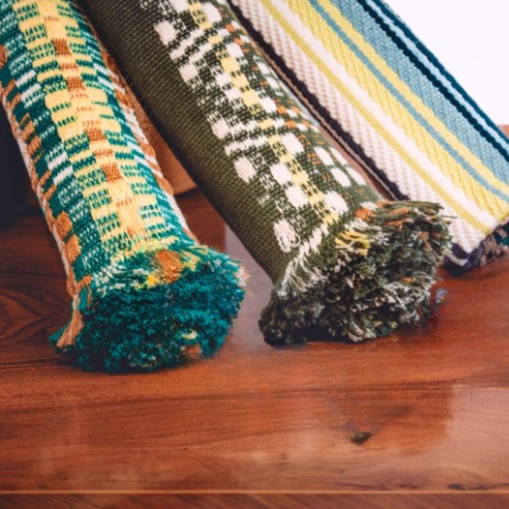 Drei handgewebte Tischläufer von Wiedengold, ruhig arrangiert auf einer Biedermeierkommode – Ausdruck kultivierter Tischkultur.