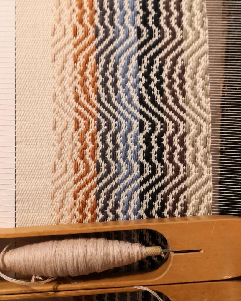 Handgewebter Tischläufer aus Wolle mit Wellenstruktur während des Webprozesses am Webstuhl.