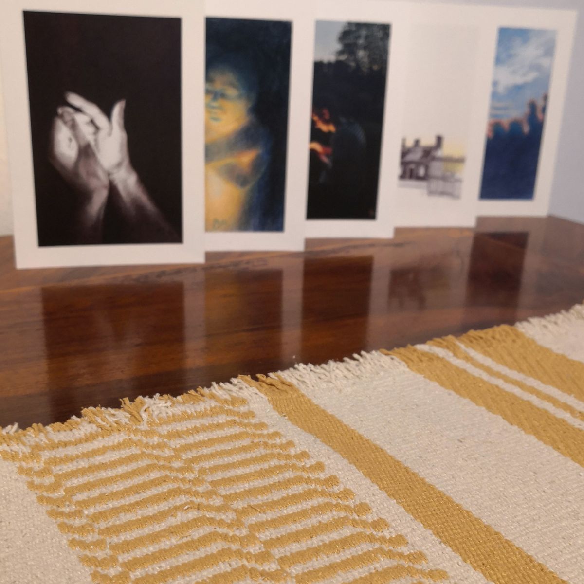 Detail eines handgewebten Tischläufers aus Bourettseide mit Kunstbillets im Hintergrund.