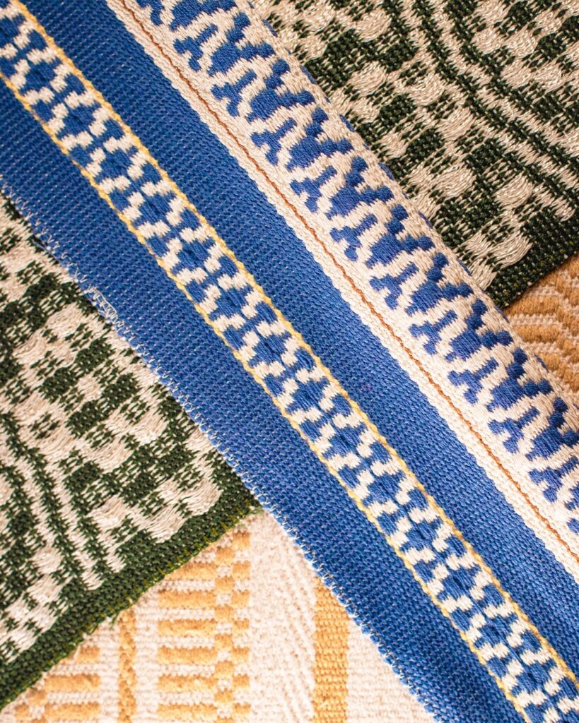 Handgewebte Stoffmuster von Wiedengold mit Streifenornamentik in Blau, Ocker, Grün und Weißtönen.